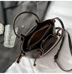 Detail view of coffee brown bucket bag with gold hardware and dual inner compartments