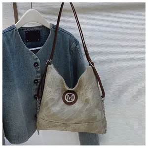 Détail du sac hobo en jean marbré avec bandoulières en cuir et logo M argenté