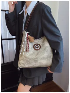Détail du sac bandoulière vintage sable avec logo M et pendentif ours en peluche