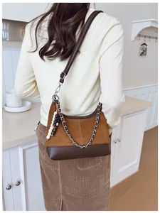 Dettaglio borsa hobo in camoscio marrone con catena argento e ciondolo a tracolla