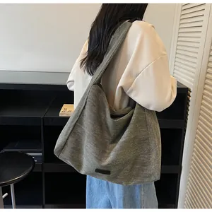 Detailed fabric texture and logo patch of the grey-green canvas tote bag on model