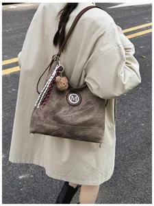 Détail d'un grand sac cabas vintage marron avec logo M en métal et breloque ourson
