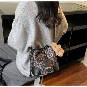 Detail of leopard print bucket bag with black leather strap and plush dog charm
