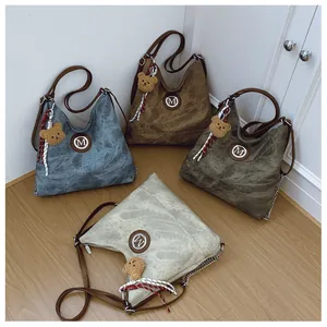 Détail montrant quatre couleurs vintage du sac hobo avec logo M en métal et accessoires