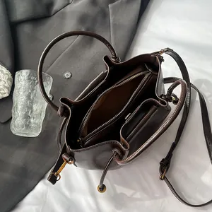 Deep brown bucket bag with central zipper compartment and adjustable shoulder strap