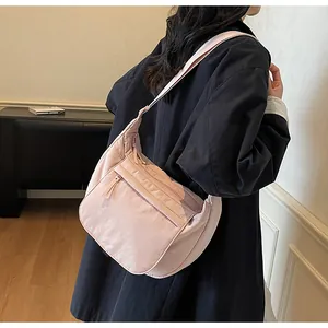 Peach pink nylon dumpling bag worn by model showing its spacious capacity and zipper details