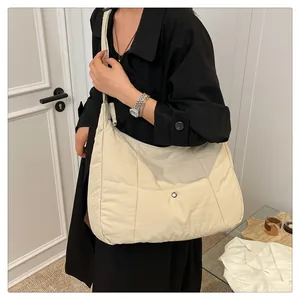 Close-up of beige quilted nylon tote bag featuring a silver metal snap button closure