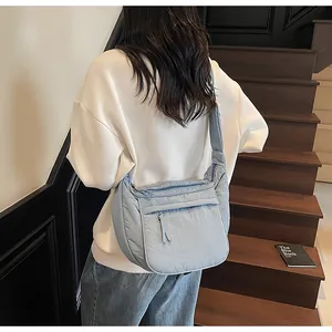 Detail of light blue crescent nylon crossbody bag with front zipper pocket and wide strap