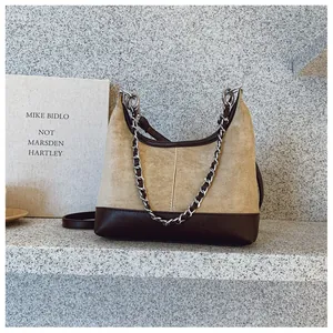 Dettaglio della borsa in pelle scamosciata kaki con base marrone e catena in argento