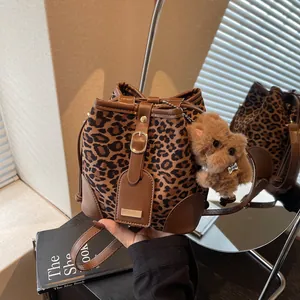 Leopard print bucket bag with leather trim and a plush dog pendant for women