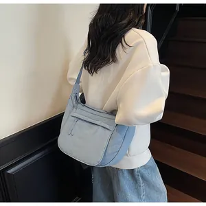 Close-up of light blue nylon crossbody bag featuring double front zipper pockets and strap