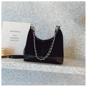 Dettaglio borsa hobo in camoscio nero con catena d'argento su sfondo in pietra minimal