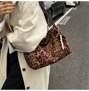 Detail of leopard print suede tote bag featuring slim shoulder strap and beaded tassel charm
