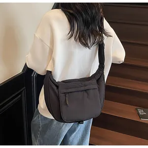 Detail of a black nylon crossbody bag with zipper pocket and adjustable wide strap