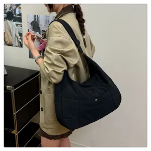 Close-up of black nylon half-moon tote bag featuring an adjustable wide strap and metal button