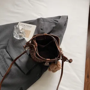 Leopard print bucket bag with brown leather trim and a cute plush bear pendant accessory