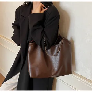 Detail of dark brown tote bag featuring lychee texture leather and chain shoulder strap
