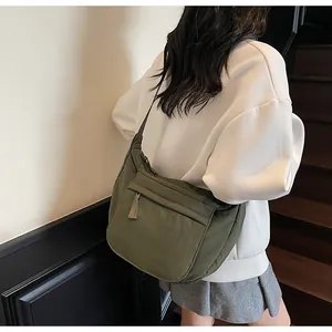 Detail of army green canvas crossbody bag featuring adjustable strap and zipper front pocket
