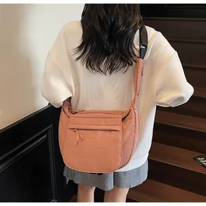 Detail of pink nylon dumpling bag featuring a wide shoulder strap and zipped front pocket