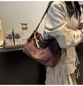 Detail of MIAOSHE embossed brown suede tote with ethnic beaded charm and soft pleats