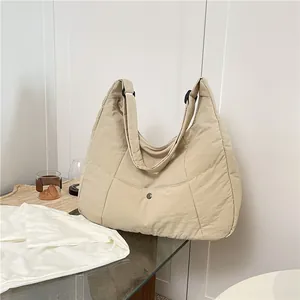 Minimalist beige quilted tote bag featuring a large capacity crescent shape and adjustable strap