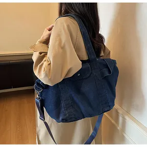 Detail view of large denim tote bag featuring adjustable strap and silver metal buckle