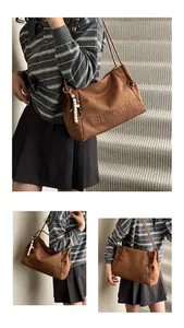 Detail of a brown suede tote bag with MIAOSHE embossing and wood bead charm accessory