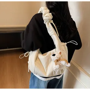 Detail of minimalist cream cloud bag featuring ruched strap and cute plush dog charm