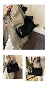 Close-up of black tote bag with embossed MIAOSHE logo and colorful wooden bead tassel charm