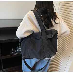 Detailed view of black denim tote bag featuring adjustable shoulder strap and metal rivets