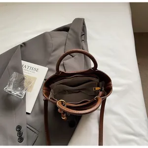 Top view of brown leather bucket bag interior with zipper pocket on grey suit background