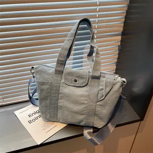 Minimalist large denim tote bag with adjustable shoulder strap and front snap pocket