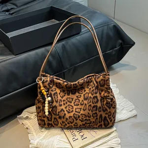 Leopard print suede tote bag with large capacity and beaded charm on white fabric