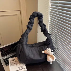 Quilted black cloud bag with scrunchie strap and cute puppy charm on a wooden desk