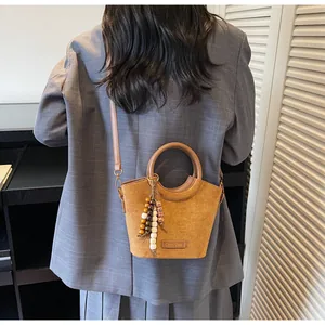 Detail of suede bucket bag with vintage bead pendant and adjustable shoulder strap