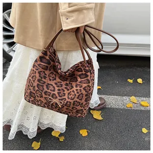 Dettaglio borsa in tessuto leopardato con manici in pelle marrone e fiocco dorato
