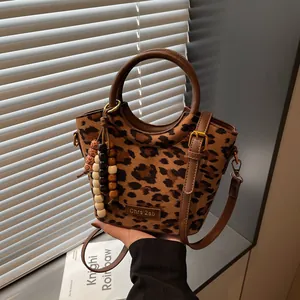 Brown leopard print handbag with leather handles and beaded charm accessory