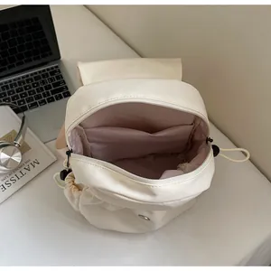 Spacious interior of canvas backpack with pink lining and laptop on white desk
