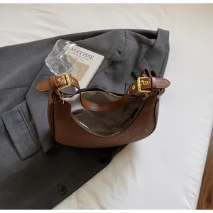 Detail view of brown leather crescent bag featuring leopard embossing and gold hardware