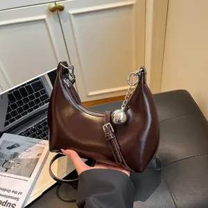 Chic dark brown crescent shoulder bag with a metallic ball charm and sleek zipper