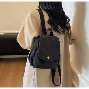 Detail of black canvas backpack with vibrant yellow button on a model's back