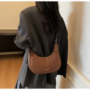 Detailed view of brown leopard print suede hobo bag with gold logo on model's shoulder
