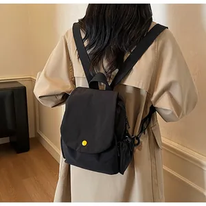 Detail of minimalist black canvas backpack with a decorative yellow button on the flap