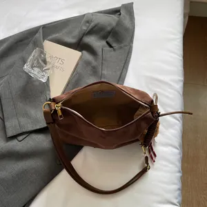 Sac fourre-tout en daim marron avec charme tressé sur de la literie blanche