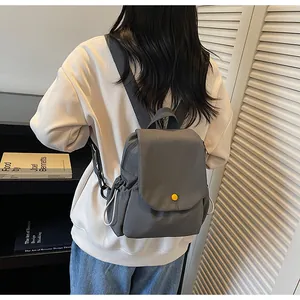 Detailed view of a dark grey mini backpack featuring a yellow snap and white drawstrings