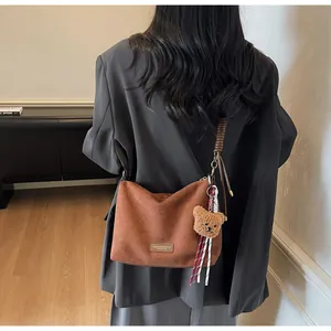 Détail du cabas en daim marron avec étiquette en cuir et un joli porte-clés ours