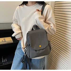 Detailed view of grey canvas backpack with yellow button and side drawstring pockets