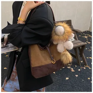 Close-up of matte suede patchwork tote bag with cute lion plush keychain in autumn setting