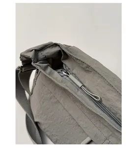 Close-up of a gray nylon crossbody bag showing the smooth zipper with matching webbing pull