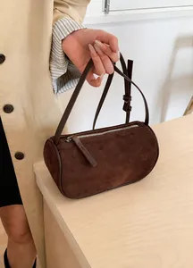 Dettaglio borsa Boston in camoscio marrone scuro su tavolo in legno per stile autunnale